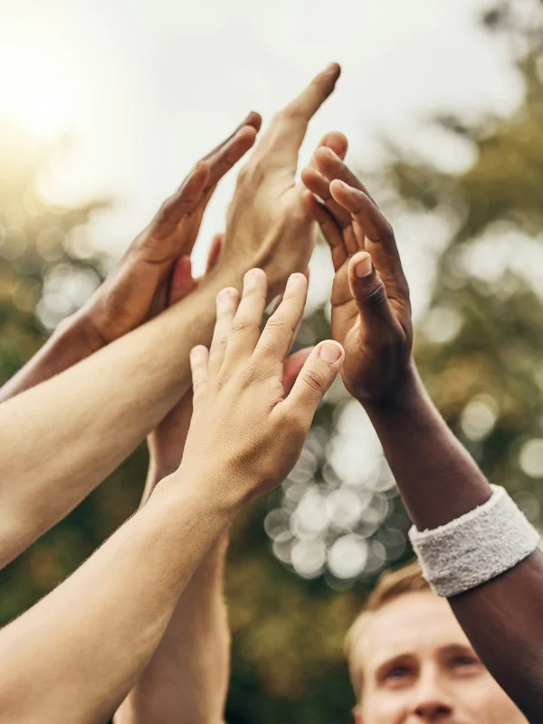 Hände schlagen zum High-Five zusammen, symbolisieren Teamarbeit.